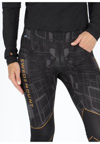 Black leggings featuring a geometric pattern in darker shades with a gold "SWEDEMOUNT" logo and two side pockets for functionality.