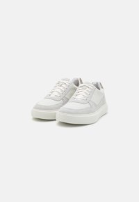 Adidași albi cu un design din materiale mixte, incluzând suede și textile. Vârf rotunjit, șireturi plate și o talpă texturată pentru aderență.
