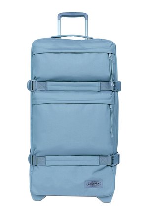 Lichtblauwe rechthoekige koffer op wielen met telescopische handgreep, twee voorzakken met rits, zijcompressiebanden en Eastpak-logo onderaan.