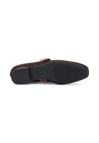 Suela de zapato de ante marrón oscuro con una superficie texturizada y un detalle de logo. El fondo claro enfatiza la forma y los materiales del zapato.