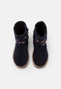Námořnické modré semišové kotníkové boty s barevnými detaily, kulatou špičkou, bočními zipy a kontrastním světlým prošíváním. Hladká textura.