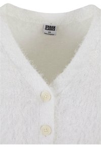 Cardigan blanc et duveteux avec un décolleté en V, doté de deux boutons, fabriqué en matériau doux, étiqueté "Urban Classics", taille XS.