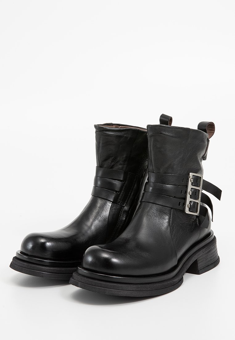 Schwarze Leder-Stiefeletten mit runder Zehenpartie, geschnallten Riemen und einer dicken, strukturierten Sohle. Verfügt über eine Zuglasche an der Rückseite für ein einfaches An- und Ausziehen.