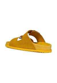 Sandal in suede giallo con punta arrotondata, tacco aperto e dettagli intagliati. Presenta una suola in gomma con bordo testurizzato.