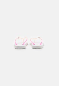 Ciabatte bianche con cinturini morbidi e traslucidi nei colori rosa e arancione, con una suola piatta. I cinturini presentano un design a forma di cuore alla base.