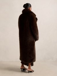 Brun pelsjakke med høy krage og lange ermer, med en teksturert, myk overflate, som rekker til midt på leggen.
