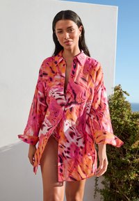 Chemise à boutons à manches longues, motif rose et orange, tissu léger et coupe décontractée, présentant des imprimés abstraits et un col.