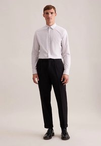 Witte geruite overhemd met knopen, zwarte geplooide broek en zwarte schoenen. Eenvoudig ontwerp met een getailleerde pasvorm en een gladde textuur.