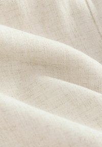 Tessuto di lino in un colore bianco sporco, morbido, caratterizzato da una superficie liscia e leggermente texturizzata con sottili variazioni nel filo.