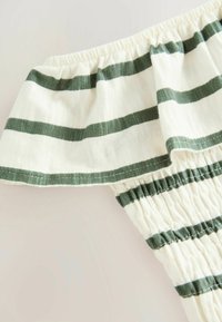 Bijela tkanina s tamnozelenim prugama, koja ima ruffles elastičnu izrez i nabran izgled na rubu, nudi ležeran i lagan dizajn.