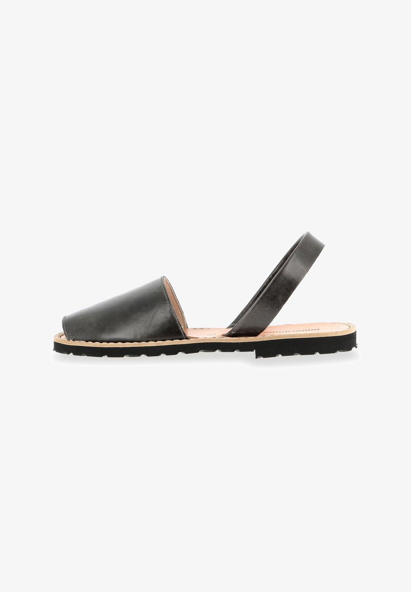 Black leather sandal with an open toe and back strap, featuring a flat sole and minimalistic design. Textured upper with stitched edges.