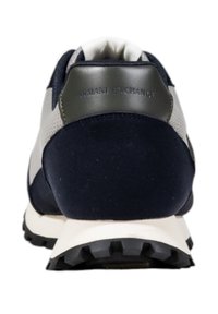 Zapatilla deportiva azul marino con un talón de ante texturizado, lados de malla y suela de goma; presenta un logo en relieve en el talón.