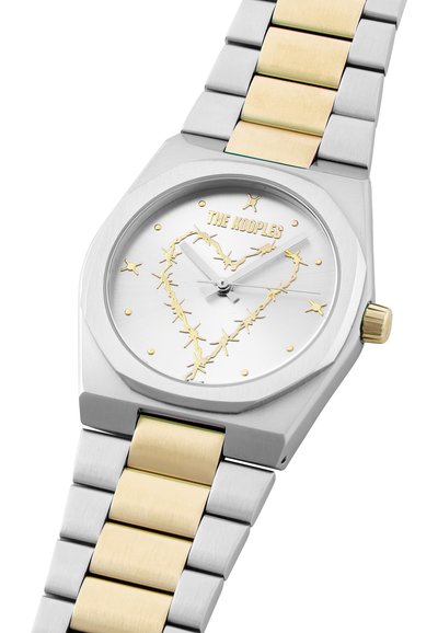 Orologio ottagonale argento con bracciale in metallo bicolore. Il quadrante bianco presenta il testo dorato "THE KOOPLES" e un design a cuore composto da stelle dorate. Corona dorata.
