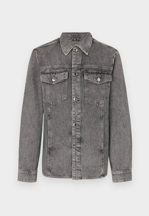 Šedá džínová bunda s límcem, zapínáním na knoflíky, dvěma náprsními kapsami a dlouhými rukávy. Má stříbrné kovové detaily a strukturovaný povrch.