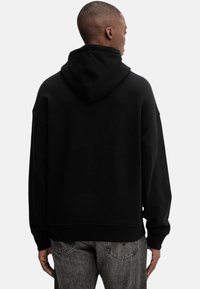 Felpa nera con cappuccio, vestibilità comoda, spalle scese, polsini e orlo a costine. Texture morbida e design minimalista.