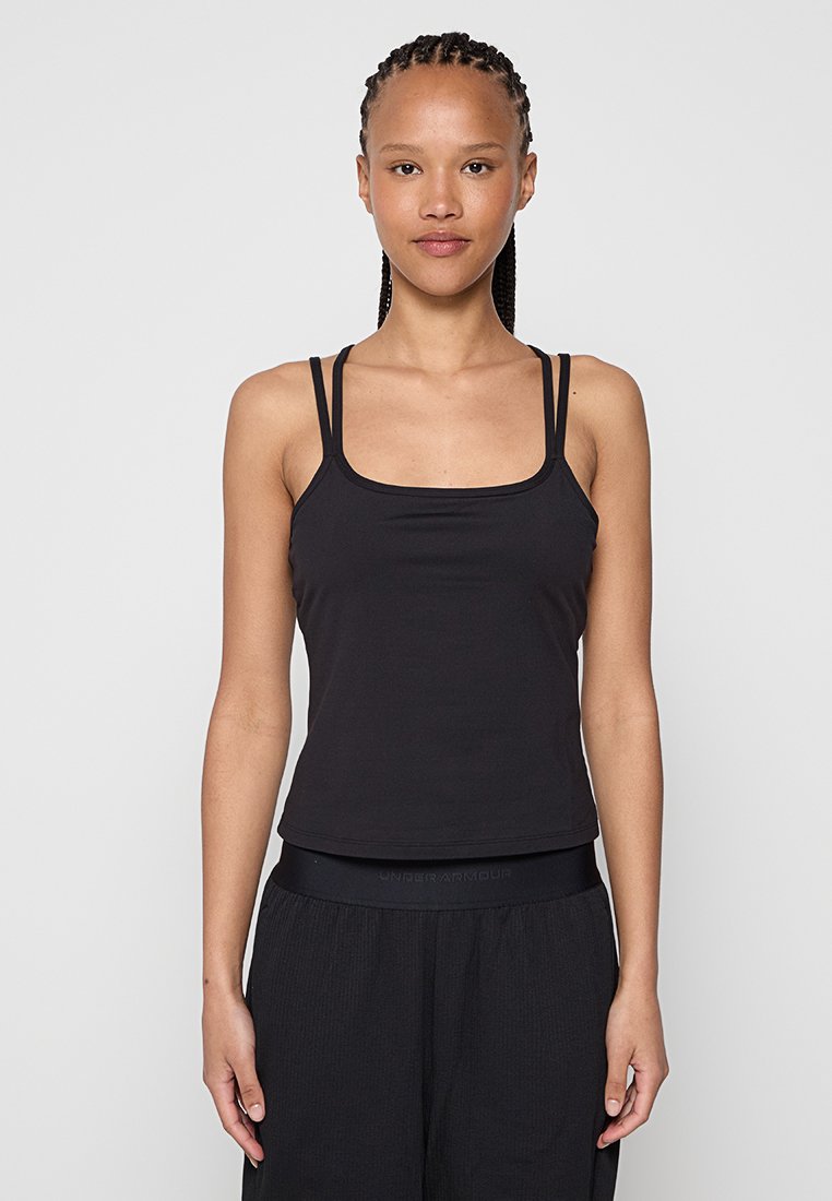 Schwarzes, figurbetontes Camisole-Top mit dünnen Spaghettiträgern, ausgestattet mit einem quadratischen Ausschnitt und einer weichen Textur. Kombiniert mit lockeren schwarzen Hosen.