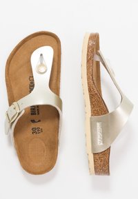 Silver Birkenstock-sandaler med korkfotbädd, en slät läderrem med en metallspänne och en strukturerad gummisula.