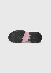 Svart gummisula på sneakers med en rosa mellansula. Har en texturerad design för grepp och en central logotypdetalj.
