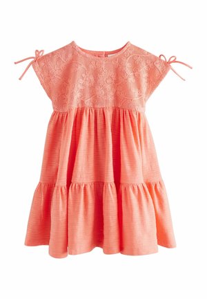 Coral dress with lace upper, short sleeves tied with bows, and a flared, tiered skirt. Made of textured fabric with a soft finish.