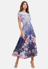 Vestido de estampado floral en lavanda y azul marino, con mangas cortas y ligeras, y una silueta fluida en A. Presenta vívidos patrones de flores.