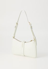 Borsa a tracolla in pelle bianca con forma curvada, accessori in oro, chiusura con zip e una tracolla decorativa con piccoli chiodi.