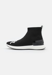 Sneaker nera in stile calza con bordo a costine alla caviglia, logo bianco sulla punta e un accento lucido nero sul tallone. Presenta una suola bianca.
