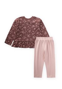 Dolga rjava cvetna majica z dolgimi rokavi in peplumsko spodnjo obrobo, kombinirana s svetlo roza rebrastimi legicami. Mehka tkanina iz bombažnega blaga po celotni površini.