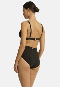 Schwarzes Bikini mit einem strukturierten Oberteil und hochgeschnittenem Unterteil. Verfügt über verstellbare Träger und goldfarbene Hardwareakzente. Glatte Textur.