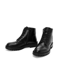 Botas de tobillo de cuero negro con cordones en la parte delantera y cremallera lateral. Parte superior texturizada, suela resistente con tacos profundos para un mejor agarre. Diseño duradero.