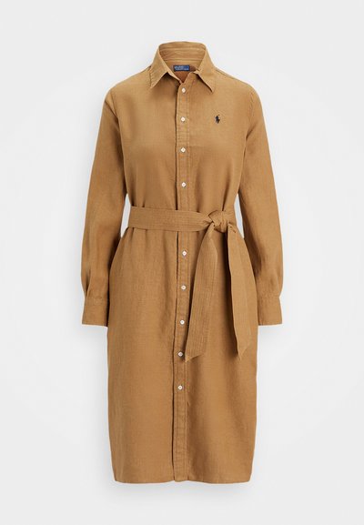 Μπεζ φόρεμα με κουμπιά φτιαγμένο από ελαφρύ ύφασμα. Έχει γιακά, μακριά μανίκια και ζώνη στη μέση με κόμπο. Λεπτό κεντημένο λογότυπο στο στήθος.