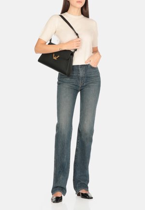 Borsa a spalla in pelle nera con dettagli in metallo dorato. Tessuto liscio, forma rettangolare e tracolla regolabile. Abbinata a un top leggero in maglia e jeans blu.