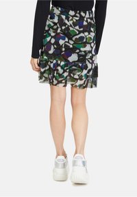Black skirt with colorful abstract pattern, layered ruffle hem, sheer texture, paired with white sneakers featuring a reflective accent.