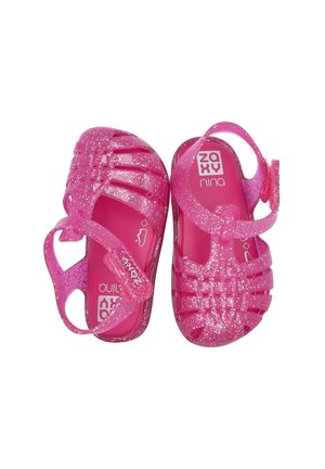 Sandalias para niños pequeños de color rosa brillante con purpurina, con punteras cerradas y correa ajustable, etiquetadas como "Zaxy Nina", dispuestas lado a lado sobre fondo blanco.