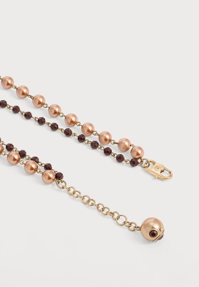 Collier chaîne ton or avec des grosses perles couleur pêche alternant avec des petites perles marron foncé, doté d'un fermoir homard et d'une chaîne extensible.