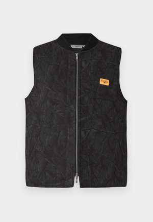 Μαύρο γιλέκο με φερμουάρ, υφασματικό μοτίβο και μια μικρή πορτοκαλί ετικέτα. Σχεδιασμένο με στρογγυλό γιακά και χωρίς μανίκια.