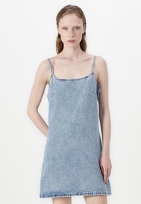 Svijetloplavi traper haljina na slip s tankim podesivim naramenicama, kvadratnim izrezom i ravnim siluetom, sa vidljivim šavovima i detaljima na rubovima.