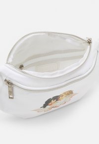 Biała saszetka na zamek z dwoma twarzami cherubów nadrukowanymi z przodu, rozpięta, aby pokazać wnętrze z małą kieszonką na zamek wewnątrz.