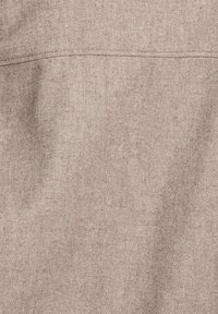 Tissu brun clair avec un tissage texturé. Présente des coutures discrètes sur le dessus ; un aspect globalement doux et lisse.