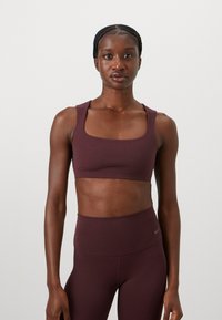 Bordeaux sports-bh med firkantet halsringning og brede stropper, lavet af strækbart materiale. Har en glat overflade og minimal branding.
