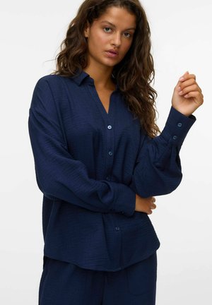 Navy blue button-up shirt with a soft, textured fabric, relaxed fit, and long sleeves. Features a collar and buttoned cuffs.