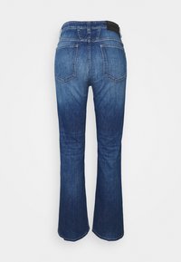 Jeans de mezclilla de un azul oscuro, de corte acampanado, lavado medio con un desvanecimiento sutil, dos bolsillos traseros y una cintura cosida con una etiqueta de cuero.
