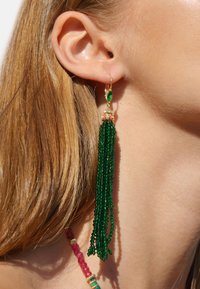 Boucle d'oreille à pampilles vertes avec quincaillerie dorée, présentant un accent supérieur de gemmes roses et vertes et une longue frange de perles.