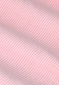 Gekreukt roze stof met een golvend patroon dat subtiele groeven en ondulaties over het oppervlak creëert. Zachte en gladde textuur.