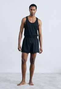 Must mustriga ja lühikesed püksid; mustriga on ümmargune kaelus; lühikeste pükste pehme kummitasku; lihtne disain, sile tekstuur, mustrid puuduvad.