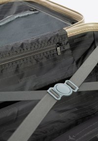 Šedá textilní vnitřek kufru ukazuje oddíly, kapsu na zip a šedý popruh s plastovým přezkou. Viditelné jsou také světlé okraje.