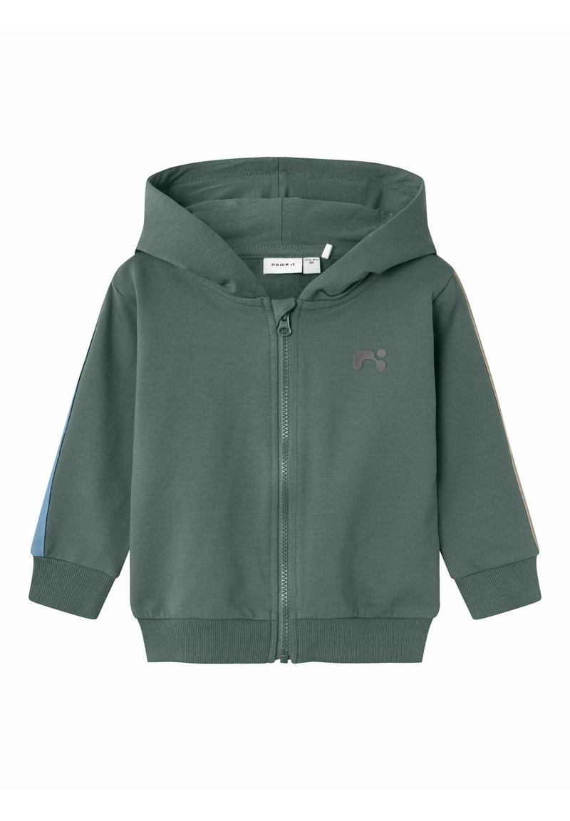 Sudadera verde con cremallera fabricada en un tejido suave, que cuenta con un bolsillo canguro, puños de canalé y detalles en azul y beige en las mangas.