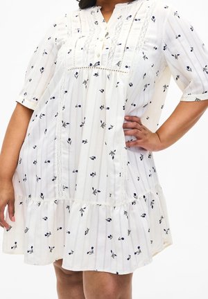 Bílé šaty po kolena s drobným tmavým květinovým vzorem, krajkovými detaily, tříčtvrtečními rukávy a vrstveným volánovým lemem.