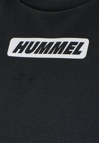Black athletic shirt featuring a textured fabric, round neckline, and a white rectangular label with the "HUMMEL" logo in bold black letters.