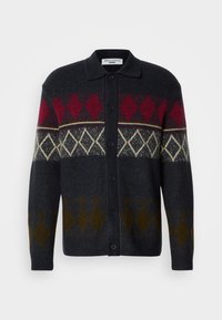 Ciemny sweter długi z wzorem argyle w kolorach czerwonym, kremowym i oliwkowym, z kołnierzykiem i guzikami z przodu.