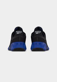 Ζευγάρι μαύρα αθλητικά παπούτσια Reebok με μπλε σόλες, εμφανιζόμενα από πίσω σε λευκό φόντο.